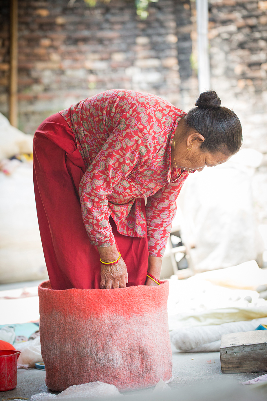 Femme népalaise en train de façonné un panier en feutre rouge et gris