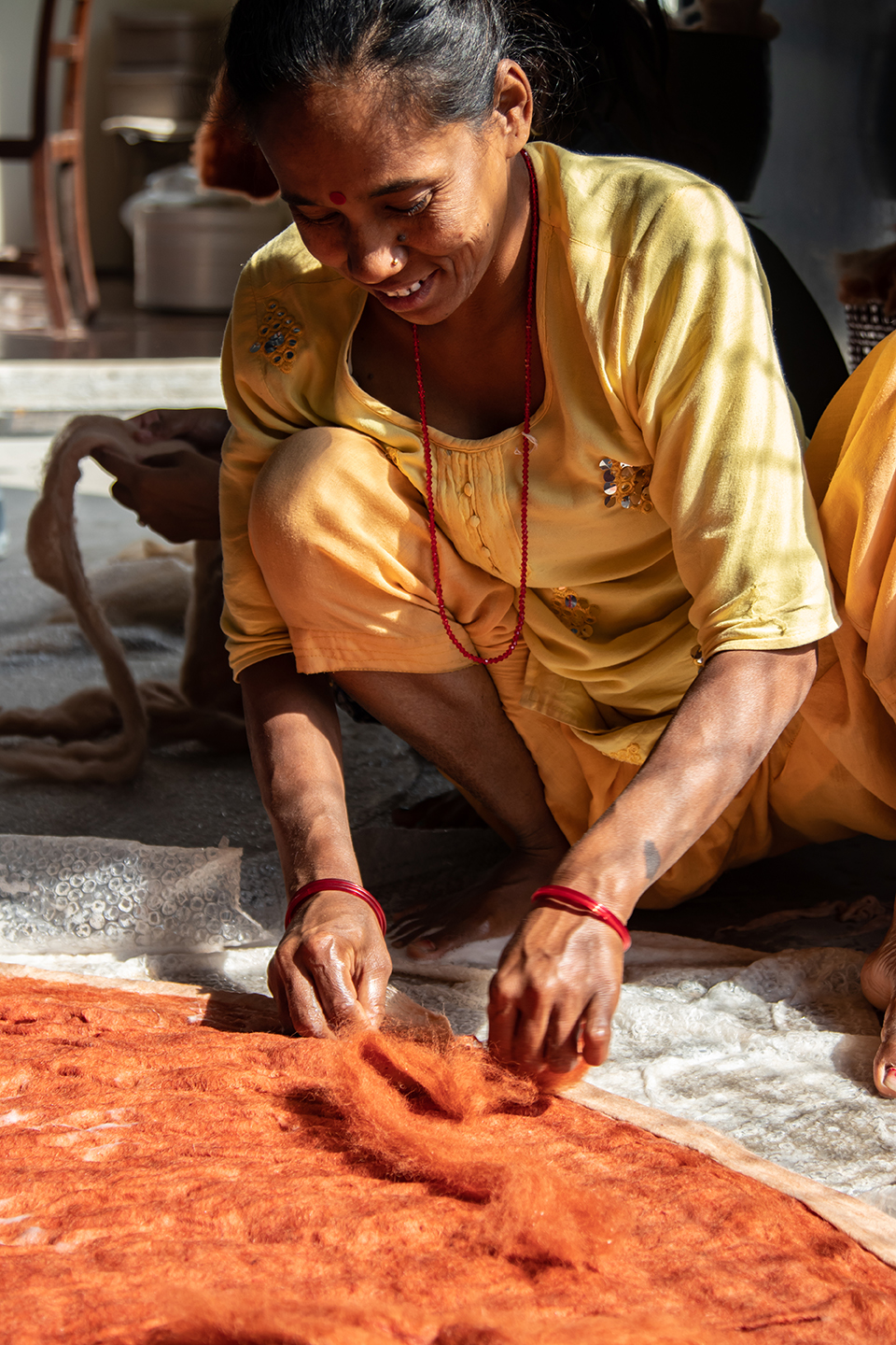 Artisane népalaise en train de poser de la laine pour la fabrication d'un tapis en laine feutrée