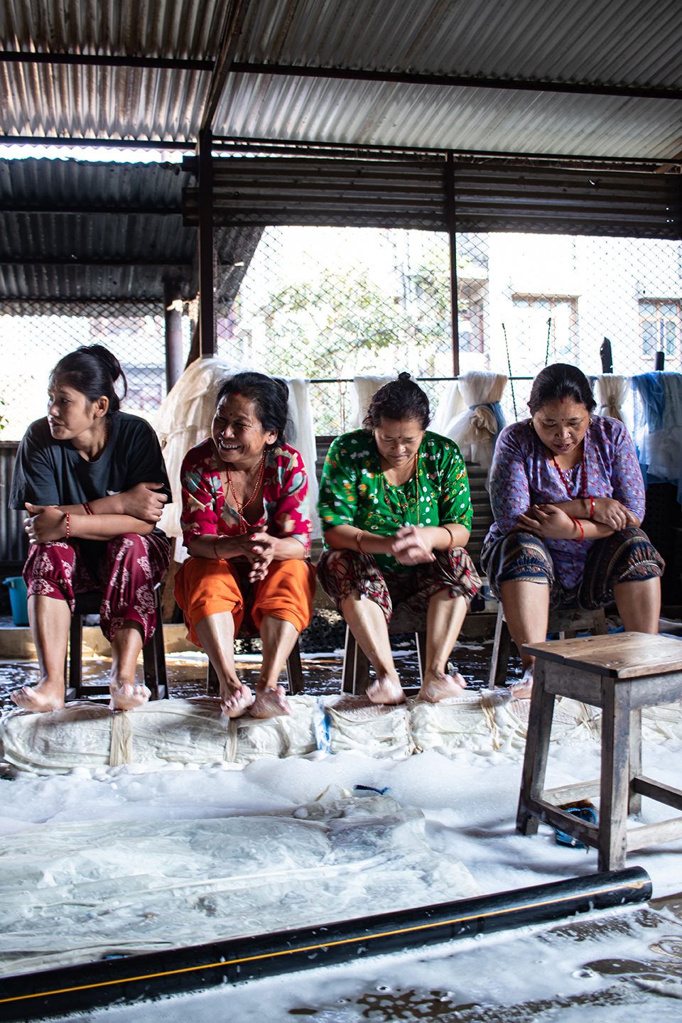 Artisanes népalaises en train de fouler au pied un tapis pour sa fabrication