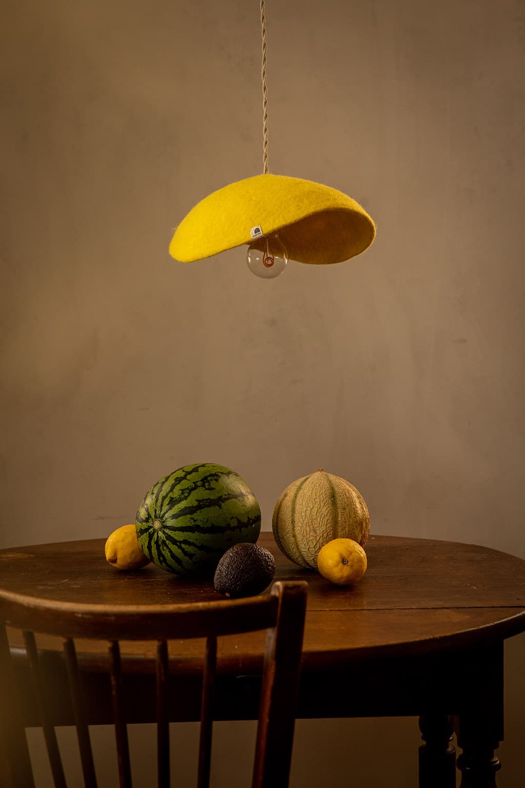 Organic yellow natural felt lampshade hanging above a wooden table