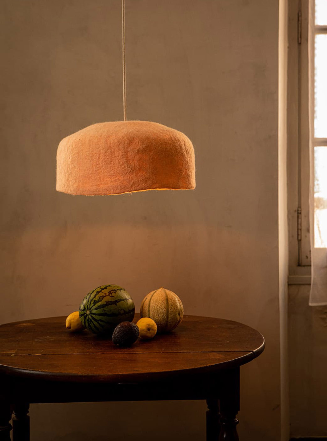 Large pink and white organic wool lampshade above a dining table