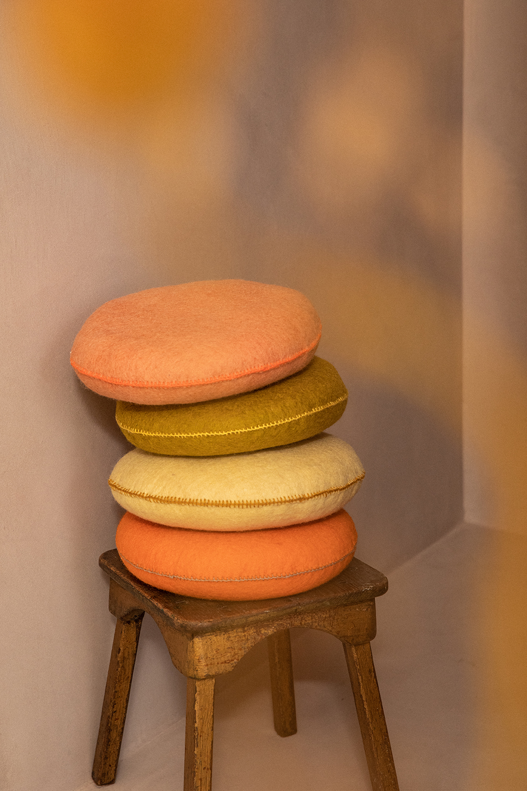 colorful pile of 4 small round cushions in pink, green, yellow and orange wool felt