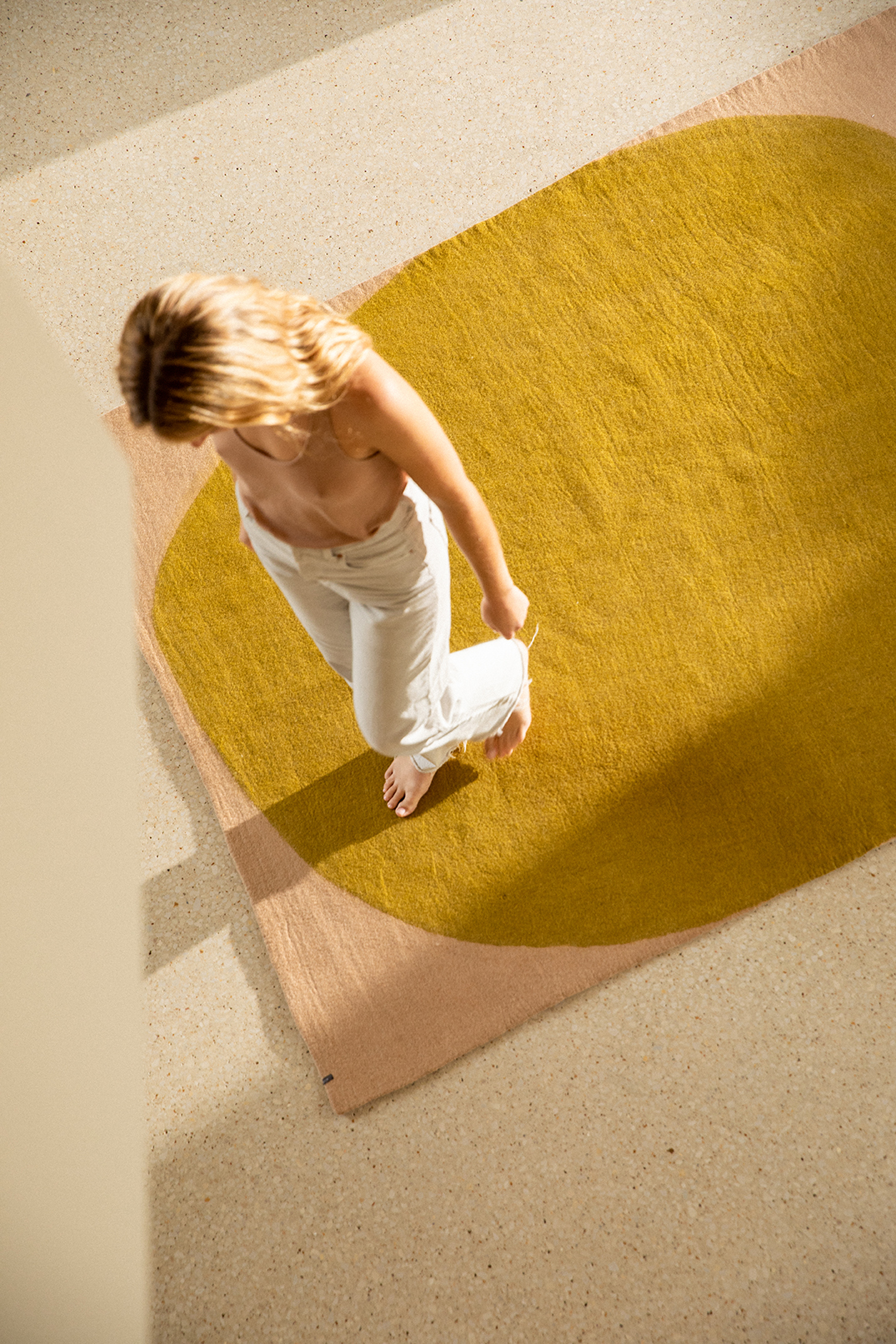 Femme marchant sur un grand tapis rectangle en feutre de laine vert et rose clair