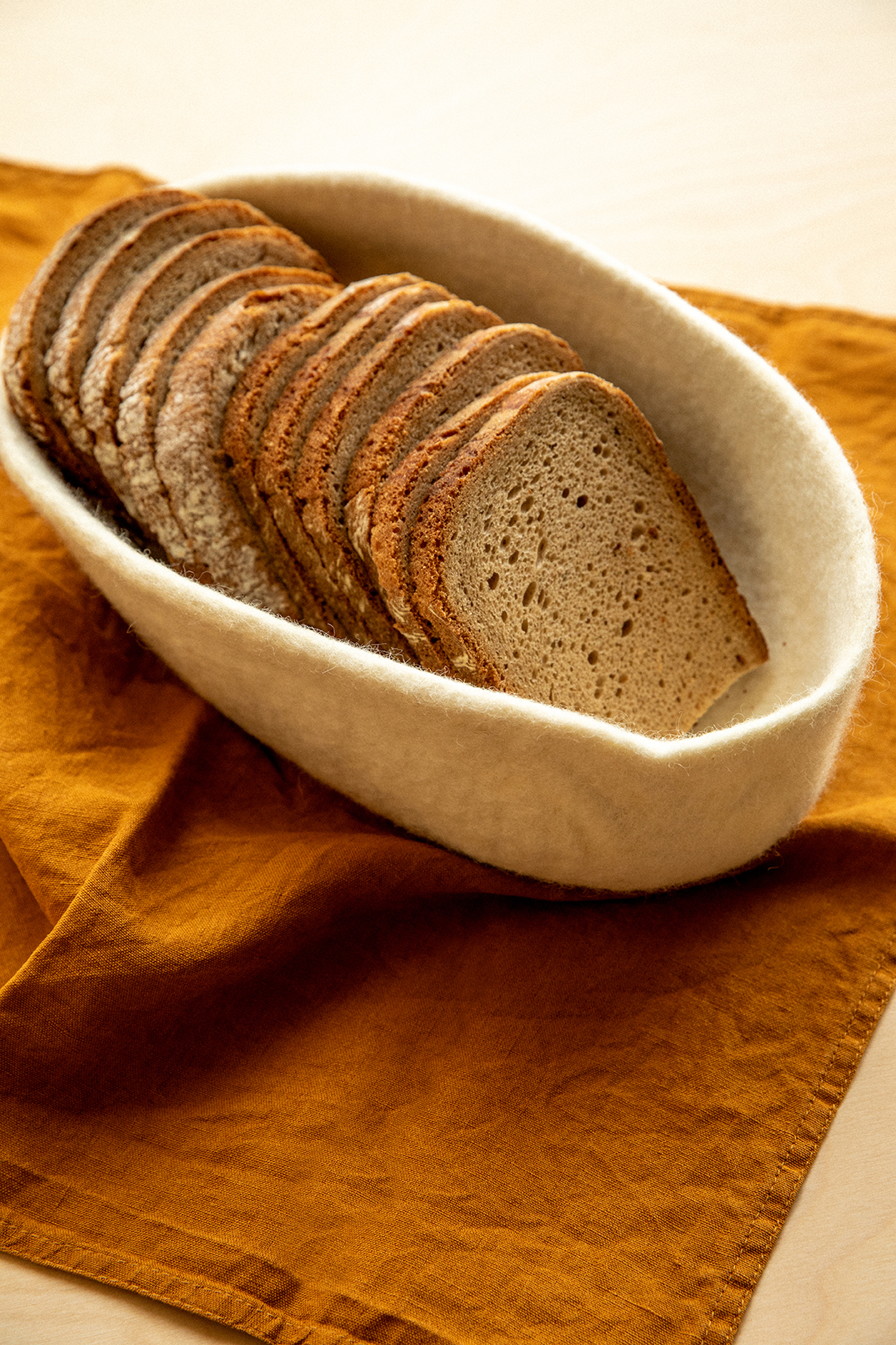 Tranches de pain dans une panière ovale en feutre de laine blanche