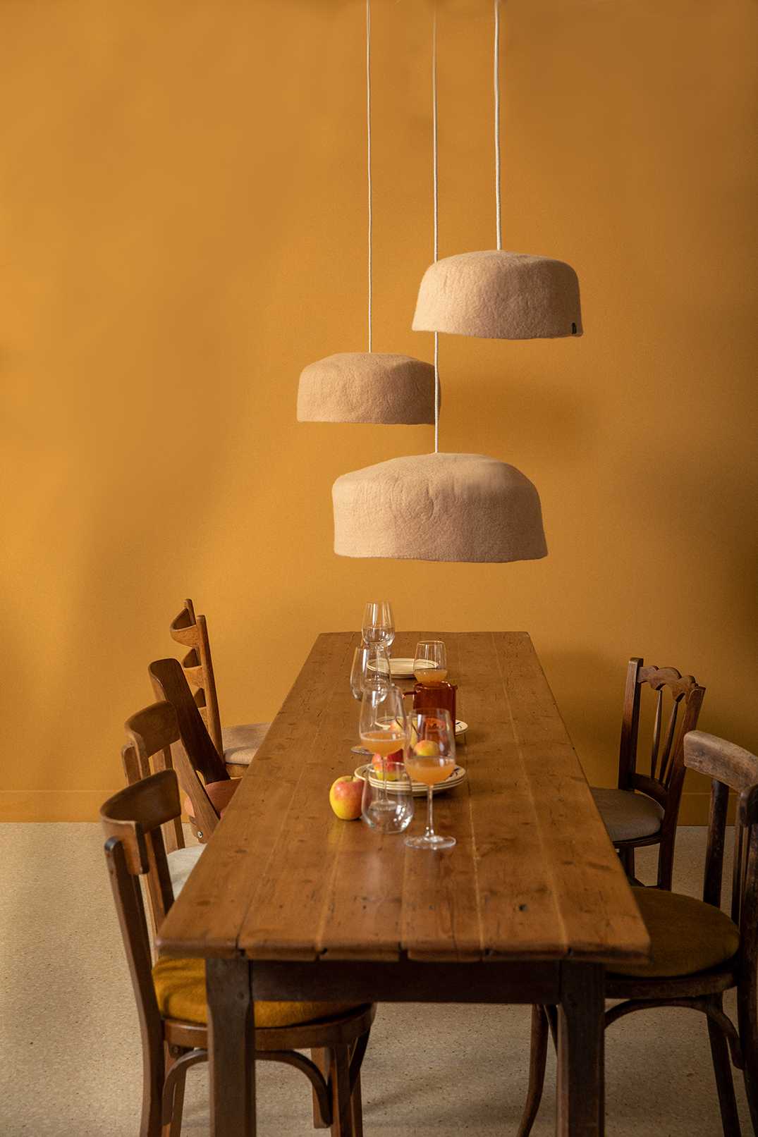Trio of light pink wool felt lampshades above a dining table