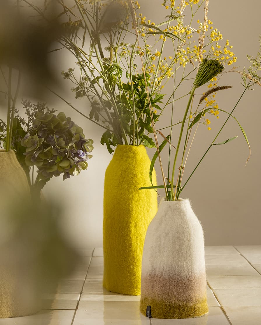 Duo de vases en laine feutrée posés sur une table carrelée