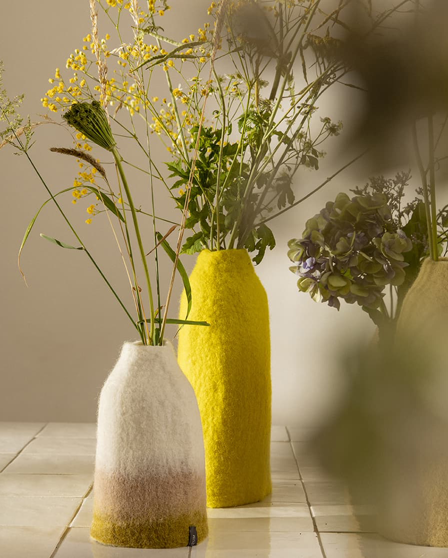 Duo de vases en laine feutrée posés sur une table carrelée