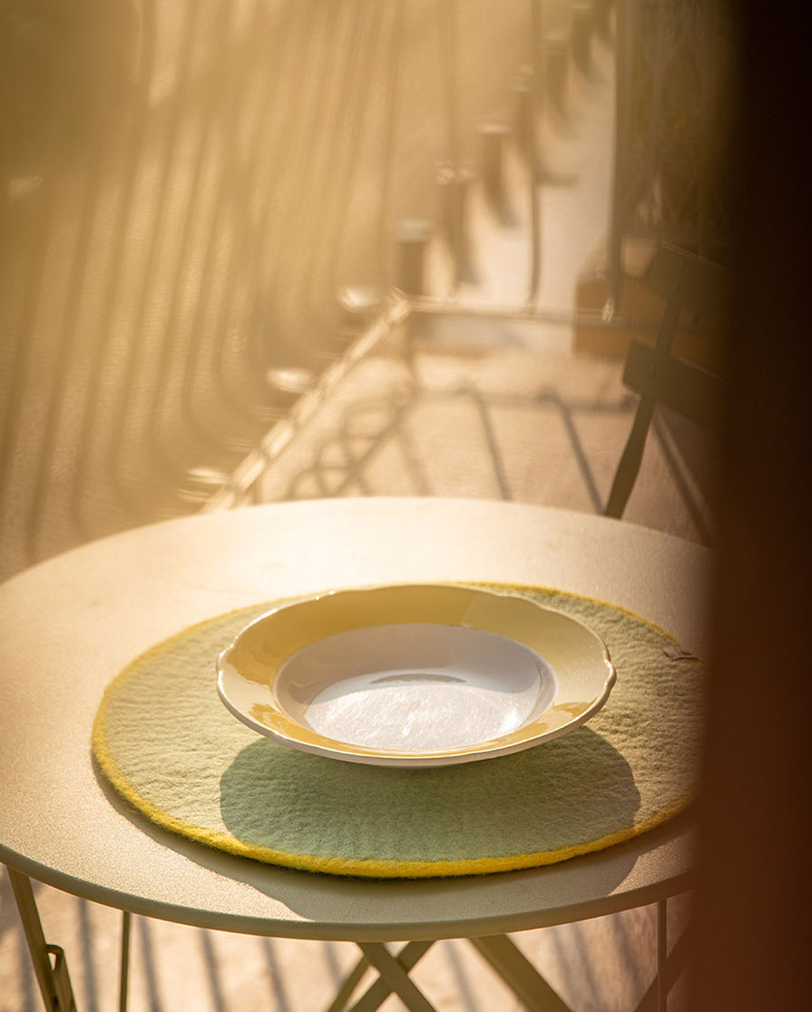 Set de table rond vert menthe en laine feutrée sur une table de jardin en métal