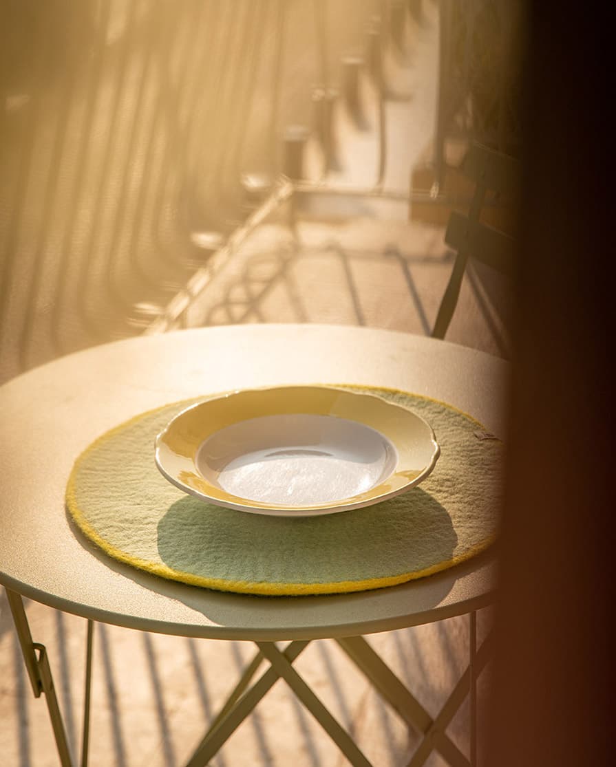 Set de table rond bicolore jaune citron et vert menthe en feutre sur une table à manger ronde en métal