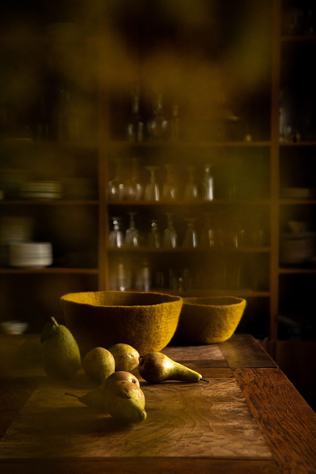 Duo of green wool felt baskets placed on a table with pears