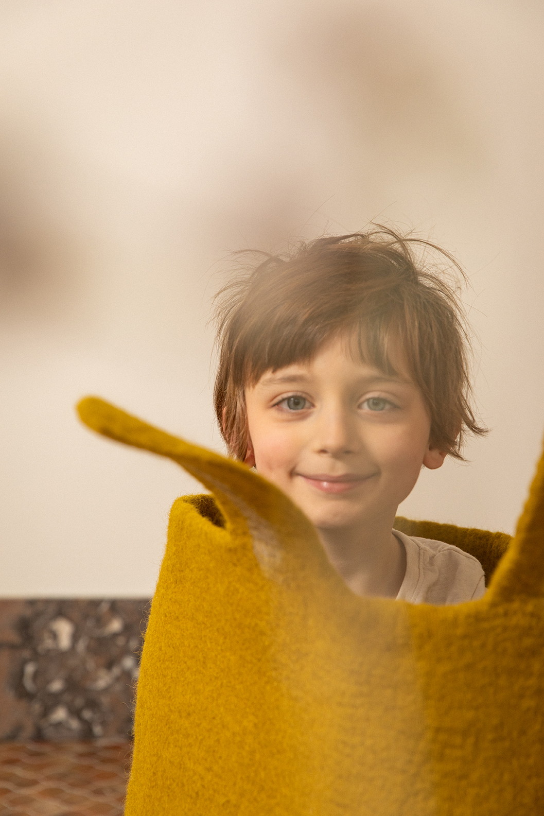 Little boy sitting in a high green wool felt basket with bunny ears