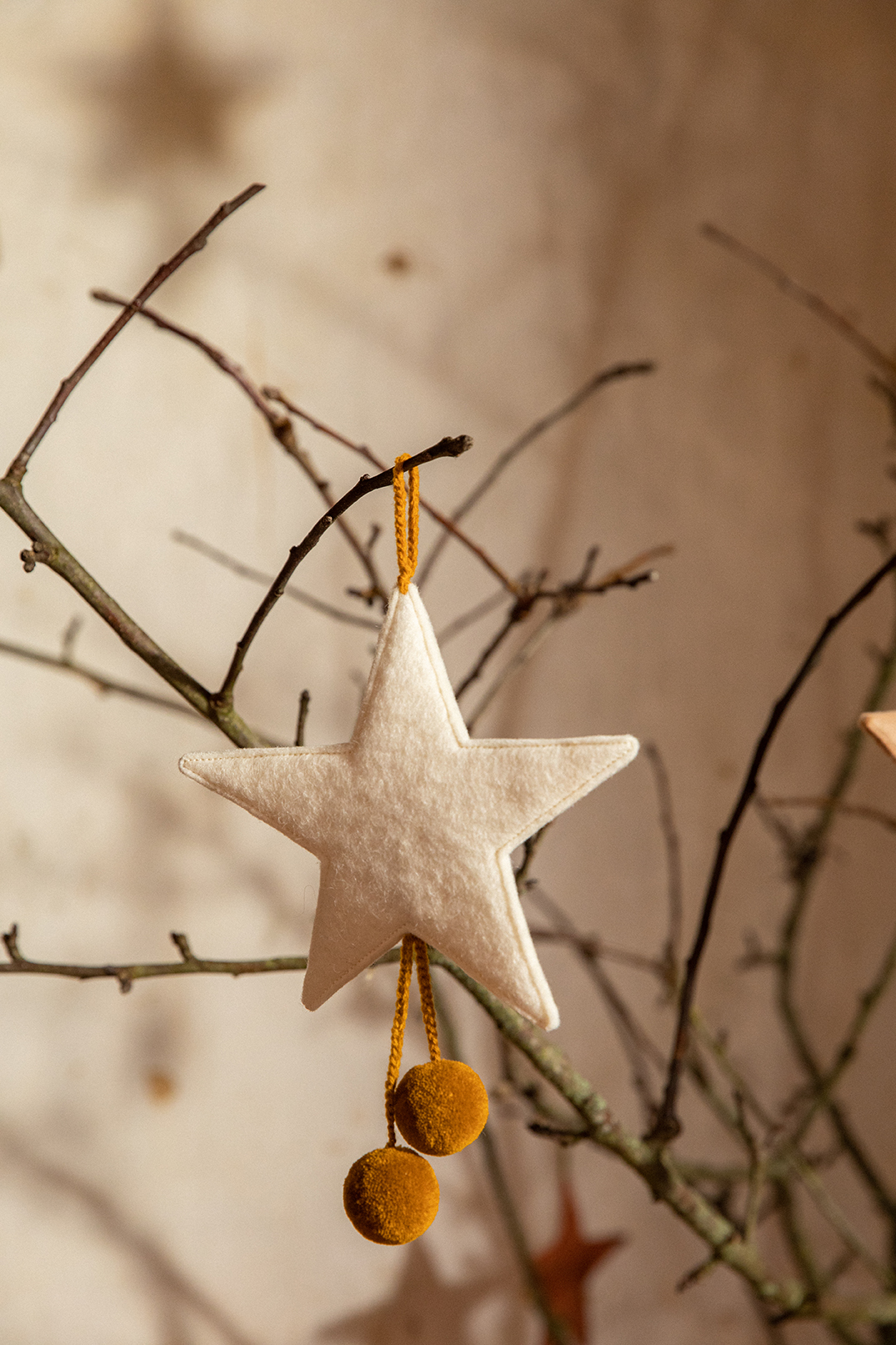 White star with yellow pompoms to hang in the Christmas tree