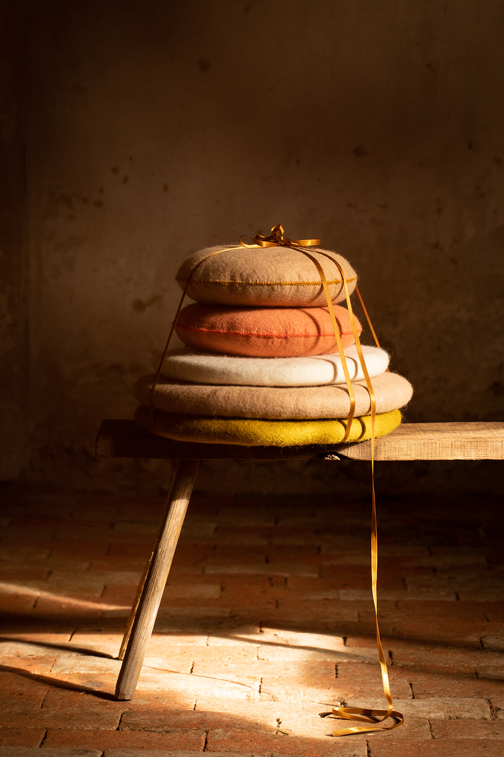 Stack of 5 boiled wool cushions on a bench