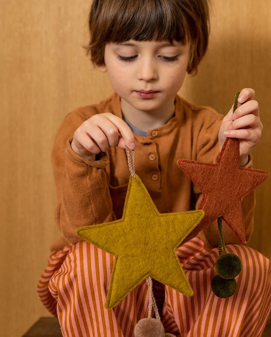 Seated boy holding a green wool felt star