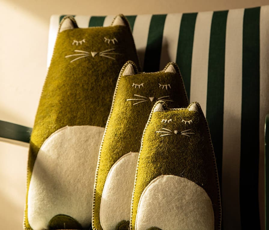 Trio de coussins décoratifs en laine en forme de chat posés sur une chaise dans la chambre d'enfant