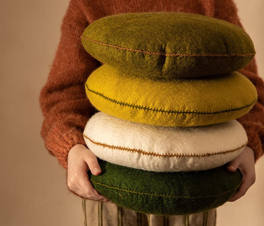 Pile de petits coussins ronds câle-dos en feutre de laine