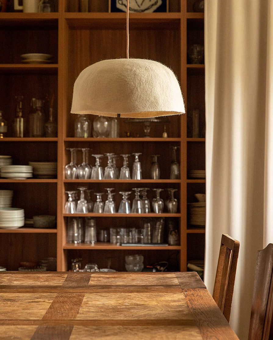 Abat-jour organique blanc en laine feutrée suspendu au dessus d'une grande table à manger en bois