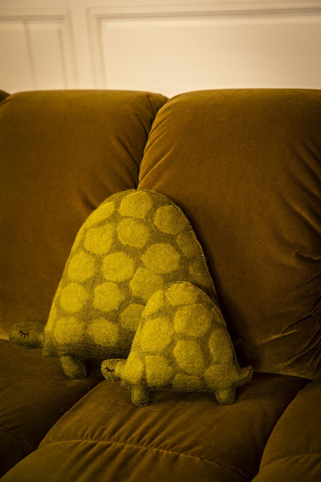 Decoratieve wollen kussens in de vorm van schildpadden op een fluwelen bank