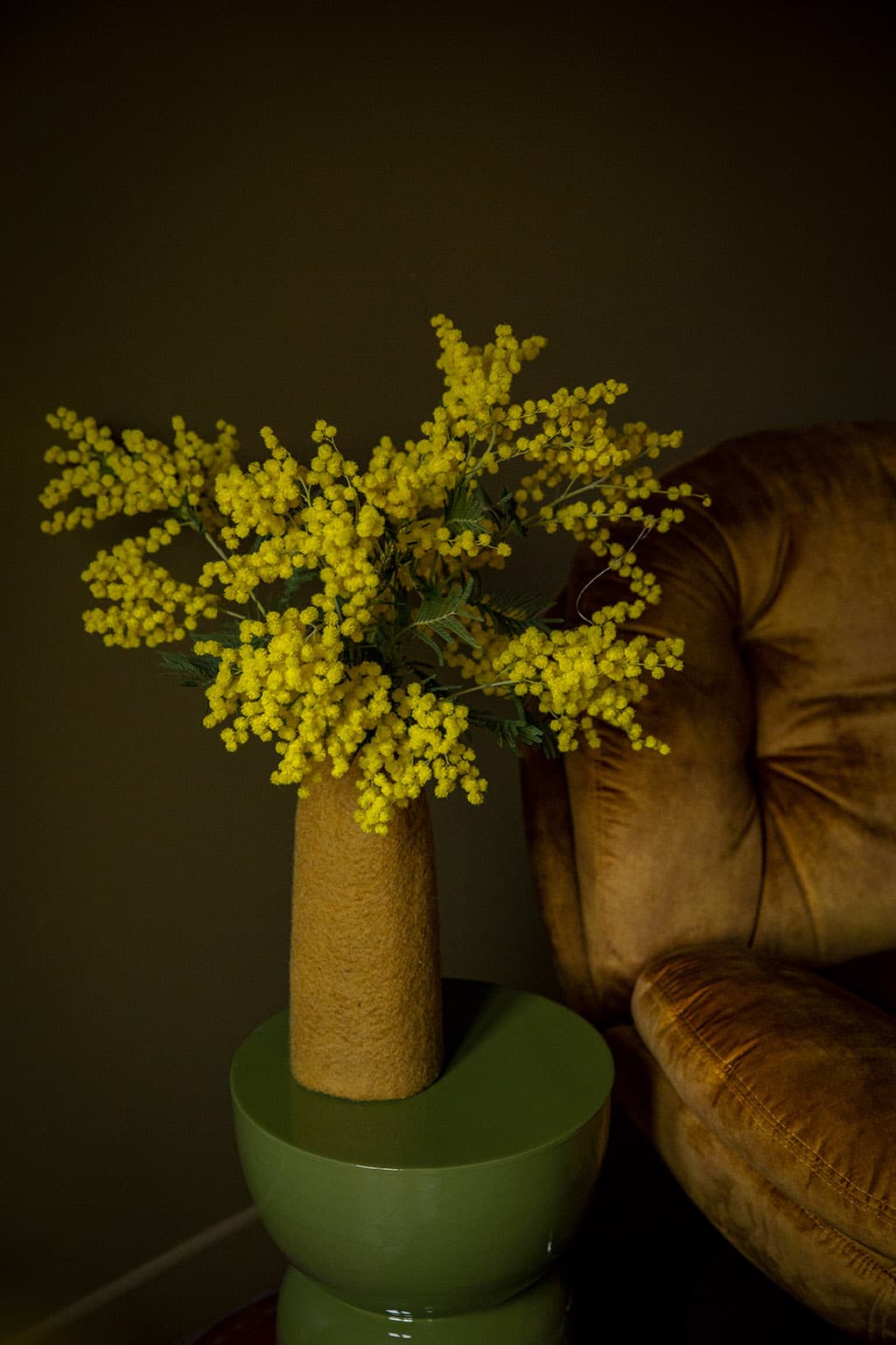 Okerkleurige wollen bloempotcover voor het decoreren van een keramische bijzettafel