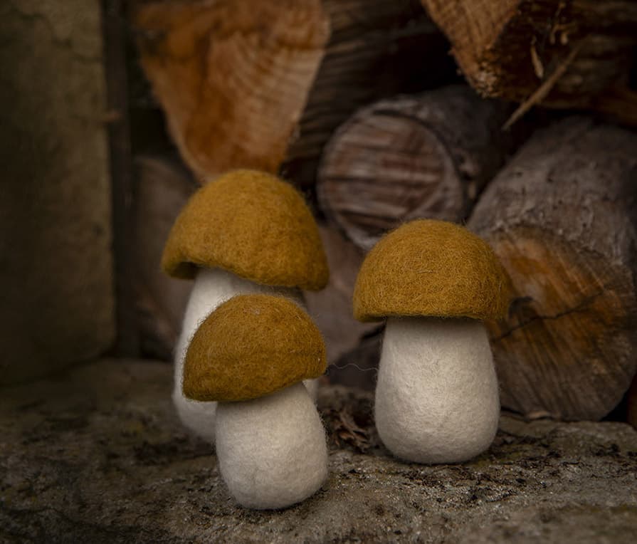 Trio van decoratieve okerkleurige paddenstoelen van wolvilt voor een landelijke sfeer