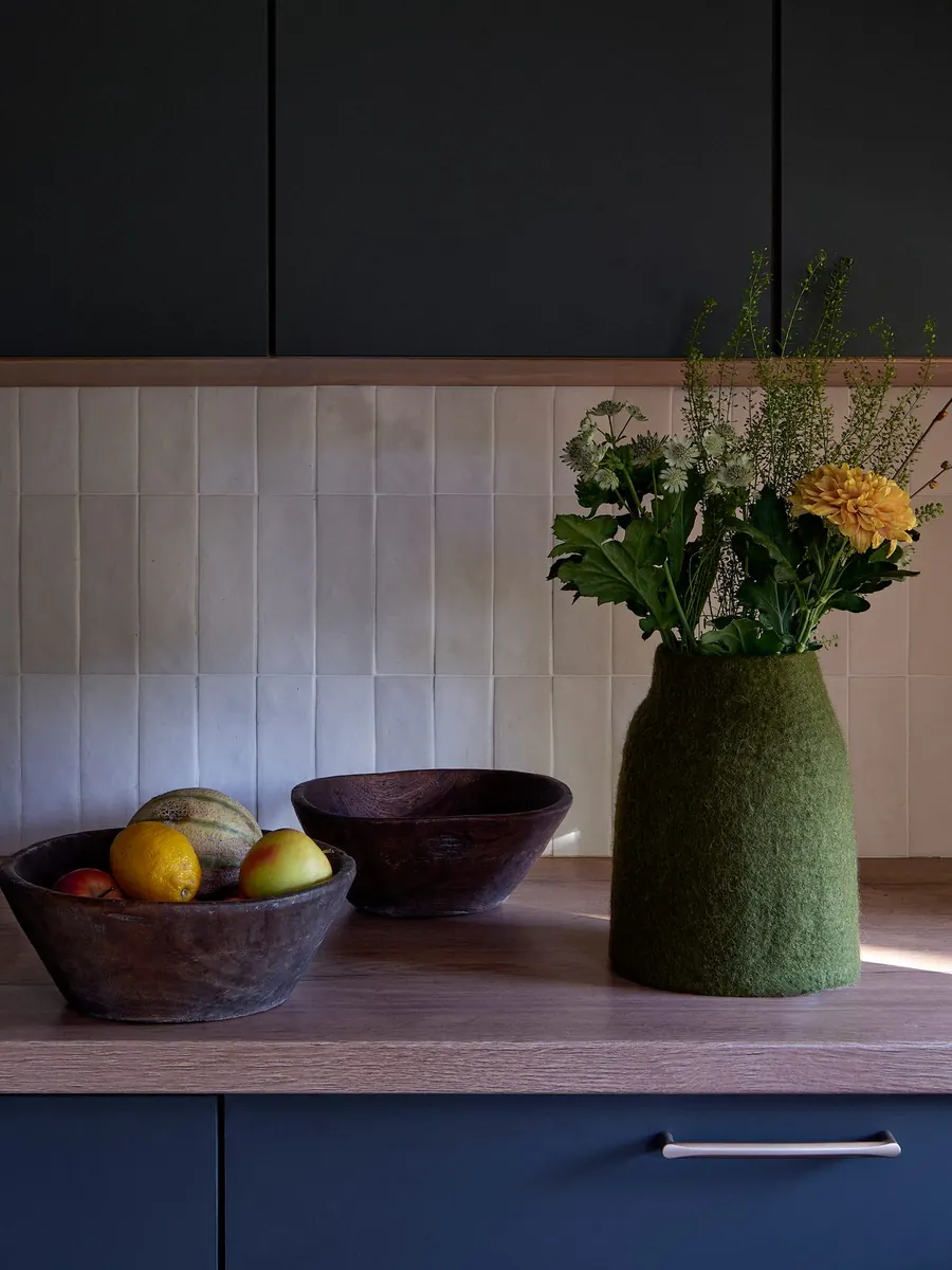 Grüne Vase aus Wollfilz mit Blumenstrauß auf einer Arbeitsplatte