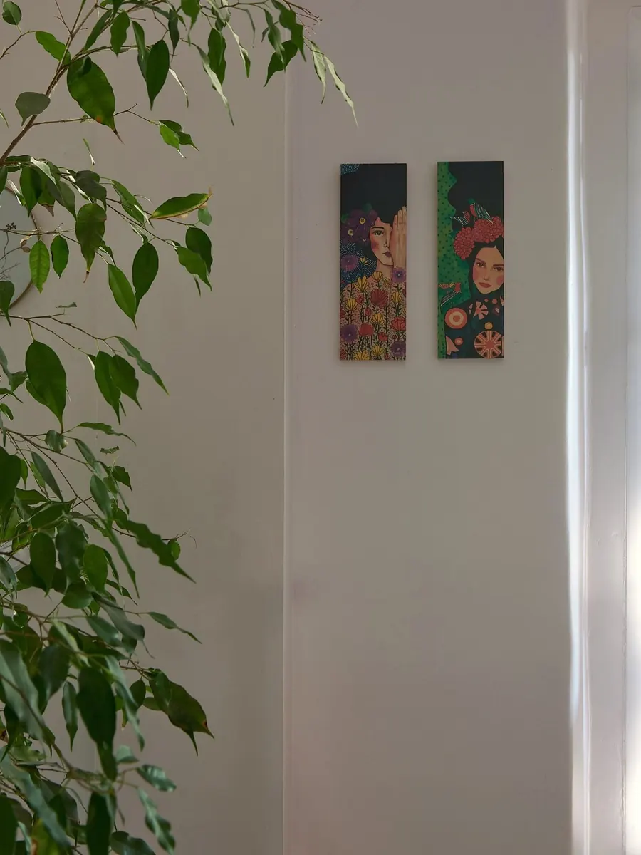 Grünpflanze und zwei Bilder an einer weißen Wand