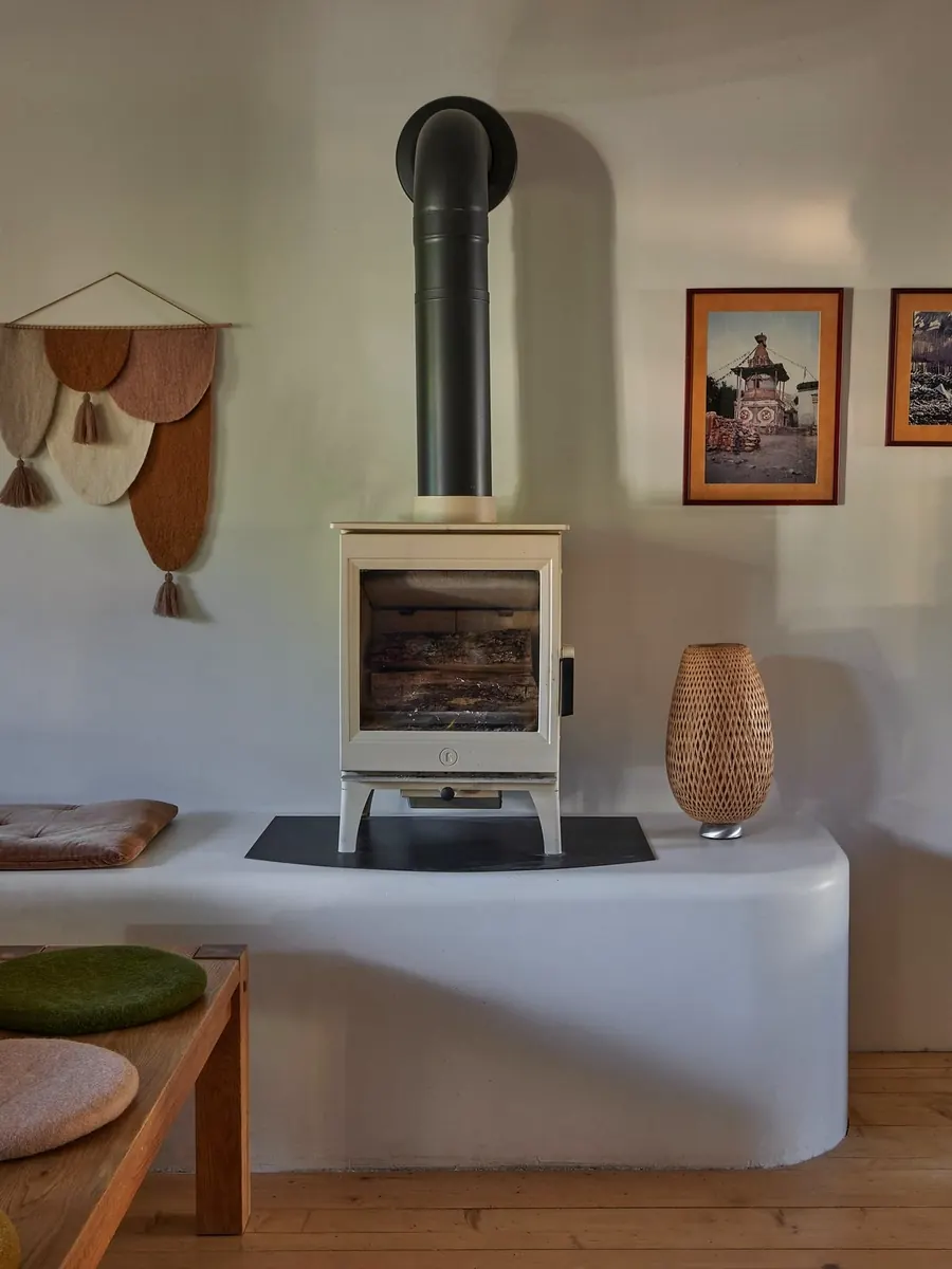 Weißer Holzofen und Wandbehang aus Filz in einem hellen Wohnzimmer