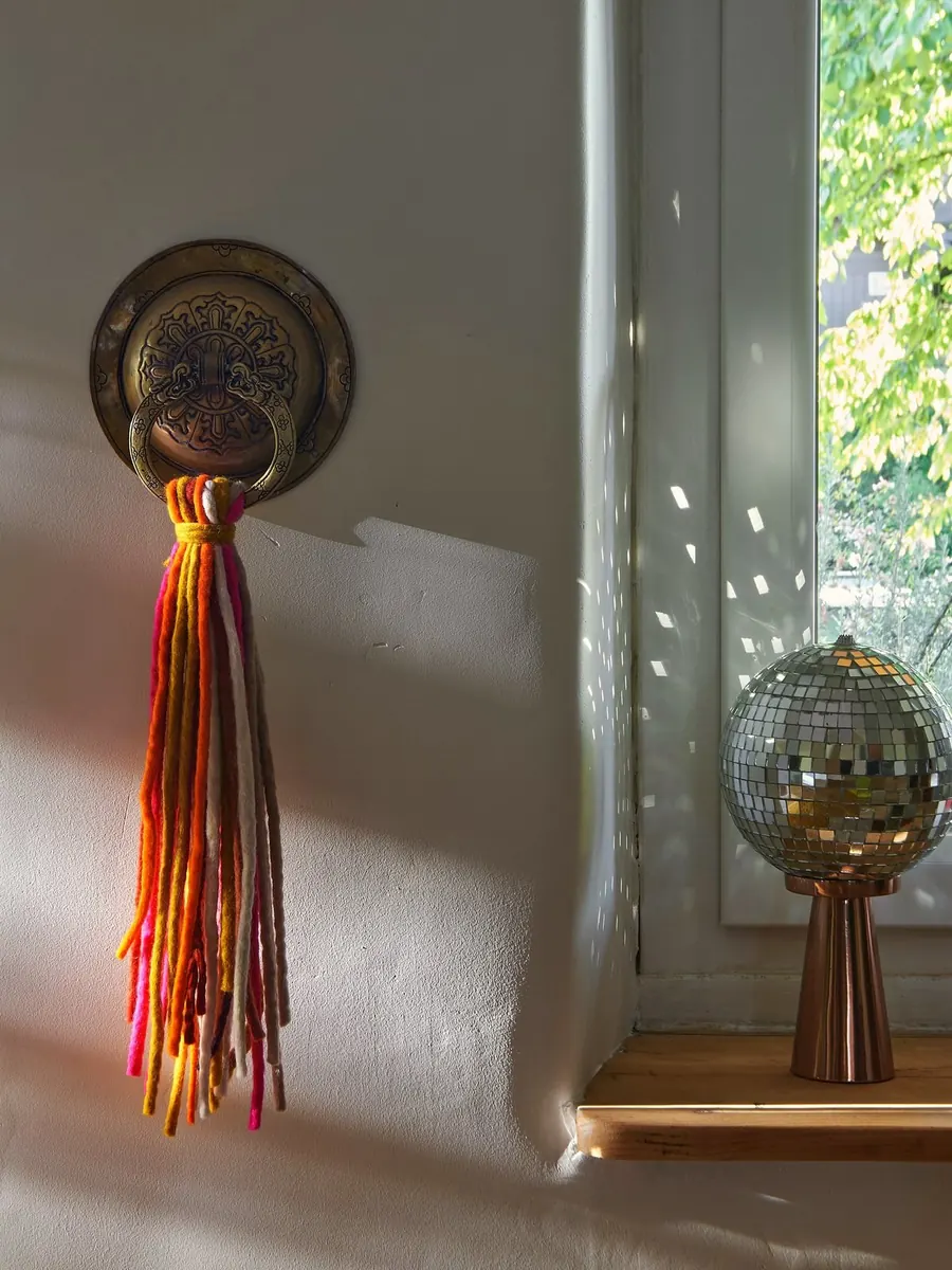 Bunte Wollquaste neben einem sonnigen Fenster