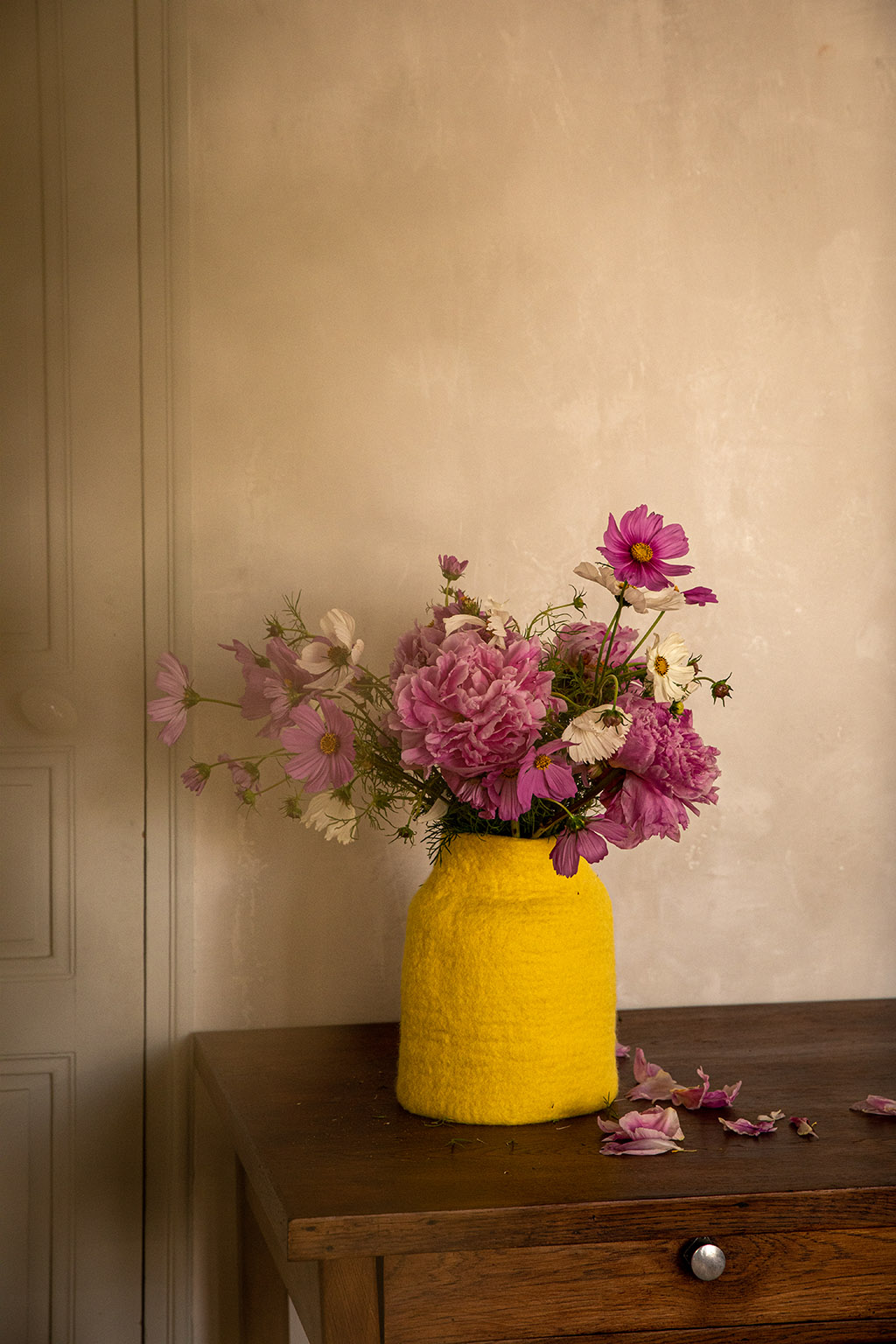 Vase jaune en feutre avec bouquet de fleurs sur une commode en bois